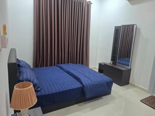 a bedroom with a blue bed and a television at The Lodge in Kuala Kerai