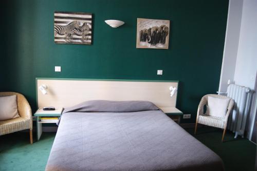 a green bedroom with a bed and two chairs at Hôtel Central in Pau