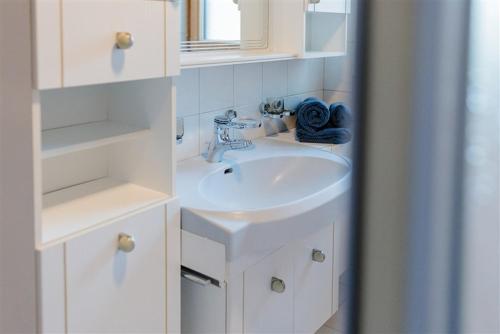 Un baño blanco con lavabo y espejo. en Apartment Anny, en Bruck an der Großglocknerstraße