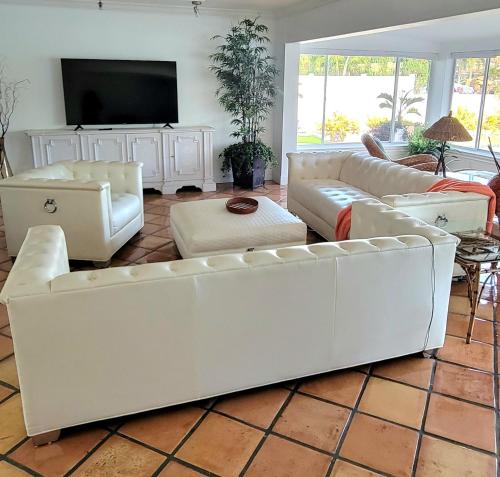 a living room with white couches and a flat screen tv at The views rental house in Pompano Beach