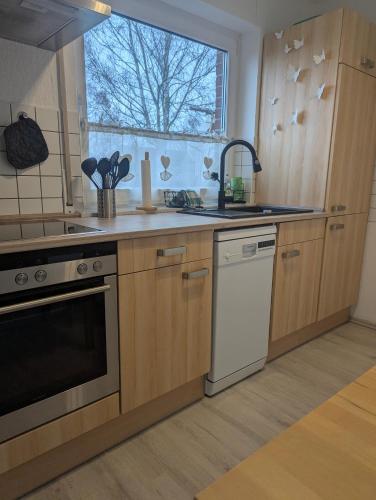 a kitchen with wooden cabinets and a sink and a window at Ferienwohnung Härtings Hygge in Obernkirchen