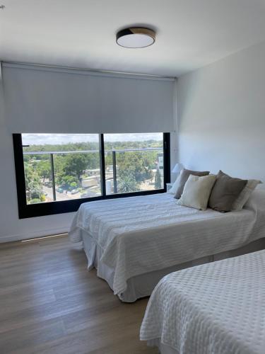 a bedroom with two beds and a large window at Apto a estrenar en Punta in Punta del Este