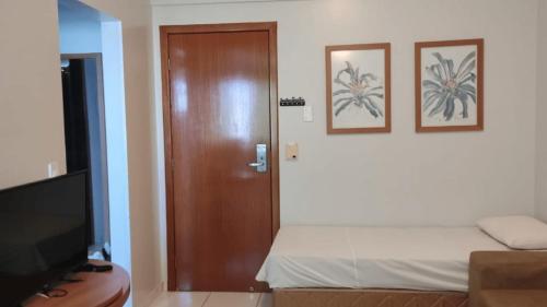 a room with a door and a bed and a television at Golden Dolphin Grand Hotel piscinas 24 hs MP in Caldas Novas