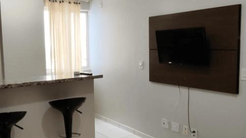 a living room with a television and a black stool at Golden Dolphin Grand Hotel piscinas 24 hs MP in Caldas Novas
