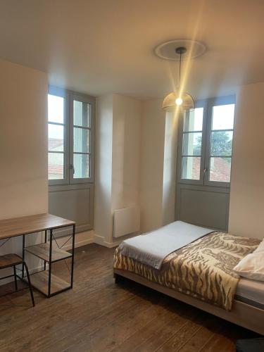 une chambre avec un lit, une table et des fenêtres dans l'établissement Chez François, à Masseube