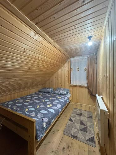 a bed in a wooden room with a wooden ceiling at У Андрушка in Vorokhta