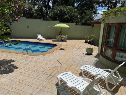 a patio with chairs and a pool with an umbrella at Mansão Adalgisa Suíte com Ar Próximo Cidade de Deus Jaguaré e Butantã in Osasco