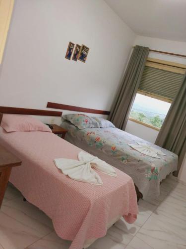 two beds in a room with a window at Hotel Nautico in Três Marias