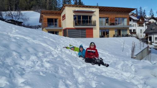 two children sitting in the snow in front of a house at Antorè in Badia
