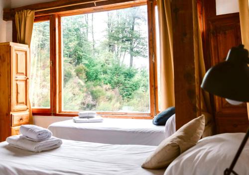 a room with two beds and a large window at Ruma Andina by DOT Cabana in Villa La Angostura
