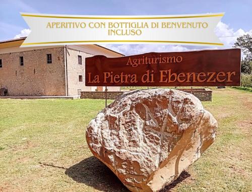 a large rock sitting under a sign in front of a building at La Pietra di Ebenezer in Filetto