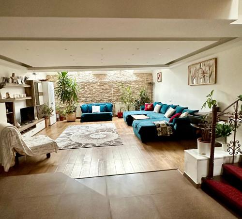 ティミショアラにあるGrazia Apartmentの広いリビングルーム(青いソファ、椅子付)