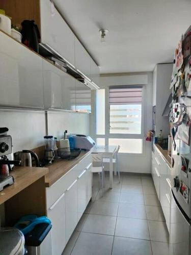 une cuisine avec des armoires blanches et une table à l'intérieur dans l'établissement Elegant 3-Bedrooms Apartment Near La Défense and Central Paris, à Colombes