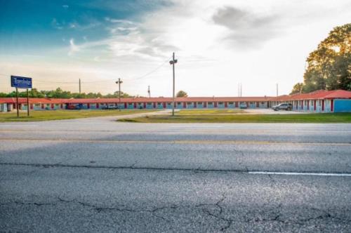 an empty parking lot with a building and a road at American Inn in Dermott