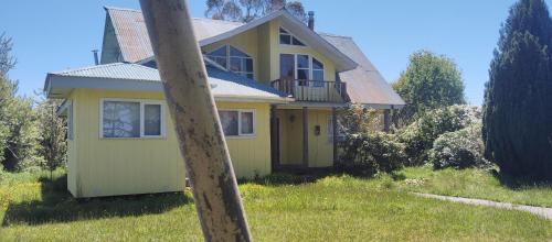 a yellow house with a porch and a balcony at Gran Casa de veraneo en Parcela Chiloe in Ancud