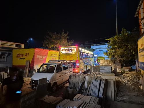 a bus and a white van parked next to a bus at Shriguru Guest House Akkalkot in Akalkot