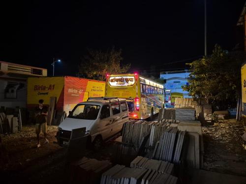 a bus parked next to a white van with a bus at Shriguru Guest House Akkalkot in Akalkot