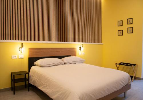 a bedroom with a large white bed with yellow walls at Lilium Suites in Rome
