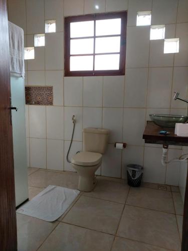 a bathroom with a toilet and a sink and a window at Cataguás Brasil Pousada in Carrancas