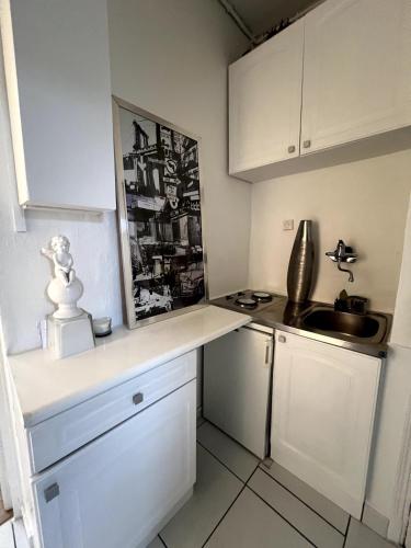 une cuisine avec des armoires blanches et un évier dans l'établissement Cocon à 5 min de Paris, à Maisons-Alfort