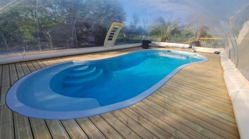 une grande piscine bleue sur une terrasse en bois dans l'établissement Gites O Ptit Bonheur - Vendée - 2 Maisons de 85 m2 chacune avec piscine extérieure chauffée & couverte, à Saint-Christophe-du-Ligneron