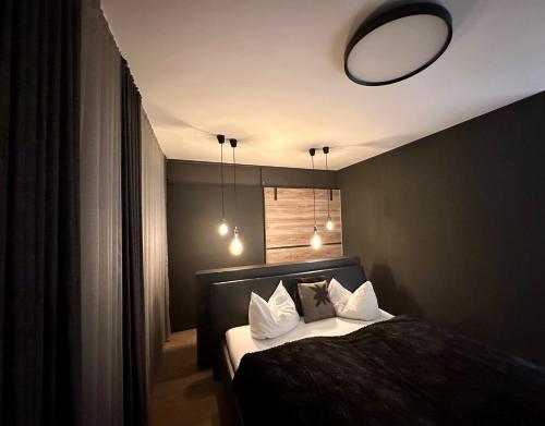 a bedroom with a bed with white pillows and a mirror at Hollywood Dream Penthouse & Apartments mit privater Sauna nahe Ischgl in Kappl