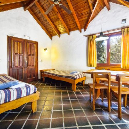a room with two beds and a table and chairs at Cabañas Am Bach in Villa General Belgrano