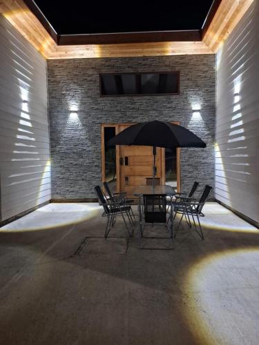 a patio with a table with chairs and an umbrella at Casa para 8 personas in Licán Ray