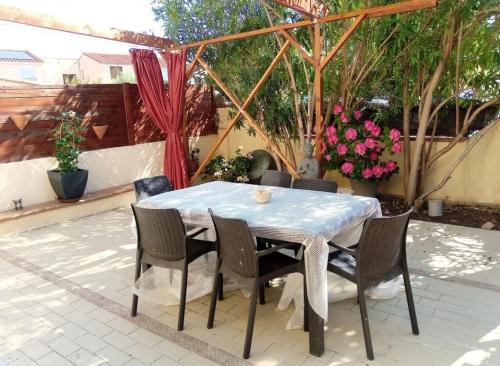 ein Tisch und Stühle auf einer Terrasse mit Blumen in der Unterkunft Maison entre mer et montagne in Pollestres