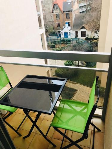 d'une table en verre et de 2 chaises vertes sur un balcon. dans l'établissement Grand studio Paris Expo Pte de Versailles Paris XV, à Vanves
