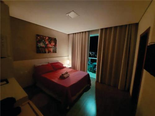 a bedroom with a red bed and a window at Flats da Júnia no Paris Residence in Lagoa Santa