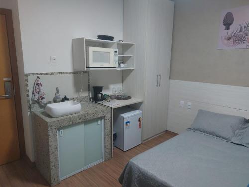 a small bathroom with a sink and a bed at Flats da Júnia no Paris Residence in Lagoa Santa