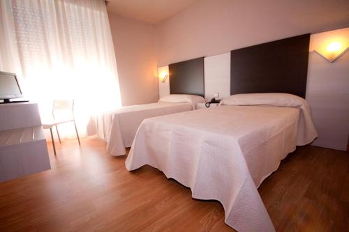 Cette chambre d'hôtel comprend 2 lits avec des draps blancs. dans l'établissement Hotel Fornos, à Calatayud