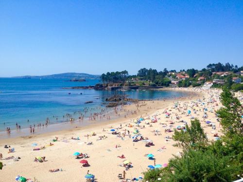 a group of people on a beach with umbrellas at White & Wood Miño Apartament in Miño