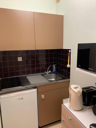 a small kitchen with a sink and a microwave at Très jolie studio à louer avec sa belle terrasse de 4m2 idéalement situé dans un hôtel thermale in Dax