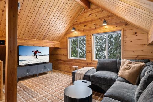Snoqualmie PassにあるAlpine Retreat at Snoqualmie Pass- 5-Min to Slopes, Private Creek, BBQ, Fireplace, Smart TVs, Kids Games, Hi-Speed Wi-Fiのソファとテレビのあるリビングルーム
