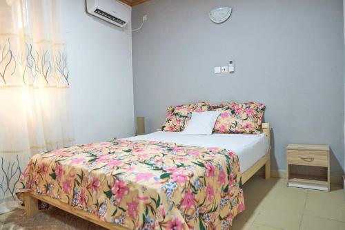 a bedroom with a bed with a floral comforter at Cosy Refuge in Bonabéri