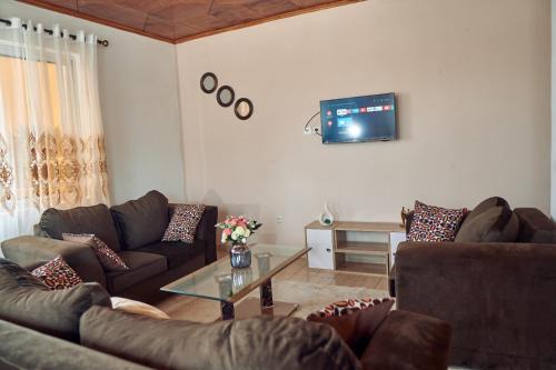 a living room with couches and a tv on the wall at Cosy Refuge in Bonabéri