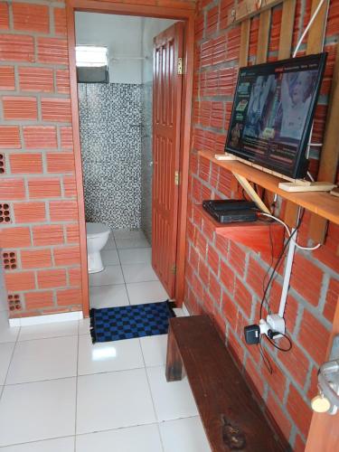 a bathroom with a tv on a brick wall at Chalé cantinho do ceu in Santo Amaro