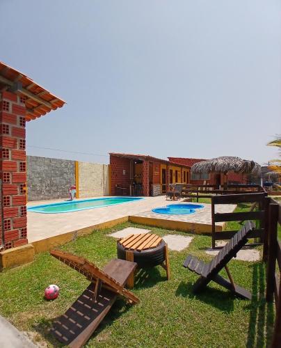 a backyard with a pool with two benches at Chalé cantinho do ceu in Santo Amaro