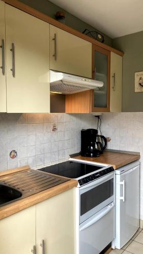 une cuisine avec des armoires blanches et un four à plaques de cuisson dans l'établissement Cottage in Normandy, à Villers-sur-Mer