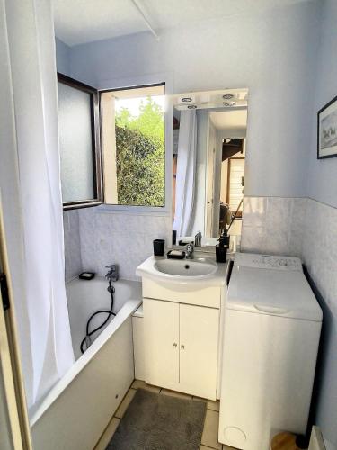 La petite salle de bains est pourvue d'un lavabo, d'une baignoire et d'un miroir. dans l'établissement Cottage in Normandy, à Villers-sur-Mer