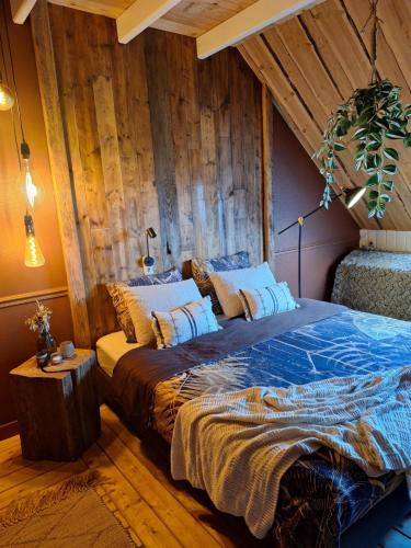 a bed in a room with a wooden wall at De Notenboom in Meliskerke