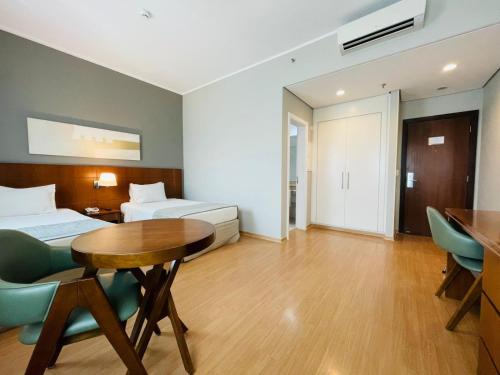 a room with two beds and a table and chairs at Luz Plaza São Paulo in Sao Paulo