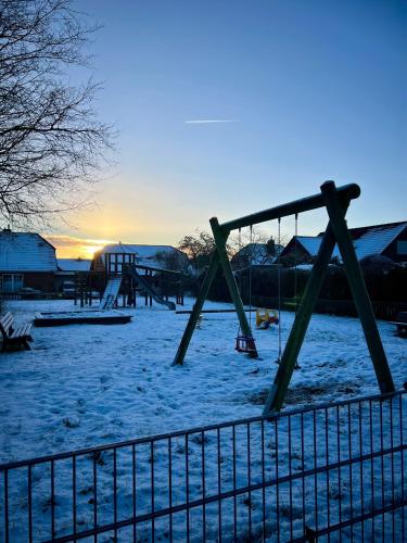 an empty playground in the snow with the sun setting at Ferienwohnung Ostseefeuer in Eutin
