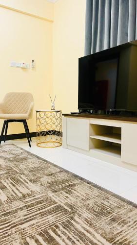a living room with a flat screen tv and a chair at المعالي Apartment مسقط in Ghursheba