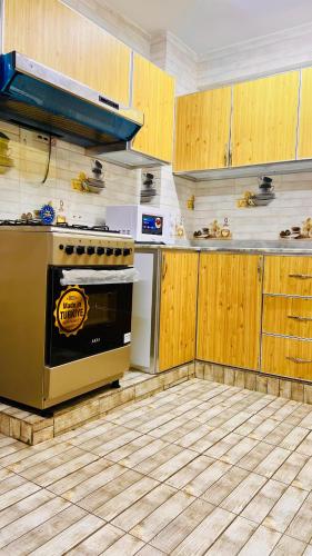 a kitchen with a stove and wooden cabinets at المعالي Apartment مسقط in Ghursheba