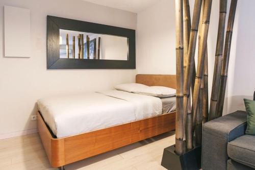 une chambre avec un lit, un miroir et une chaise dans l'établissement Le Rivieira garage et terrasse, au bord du Lez, à Montpellier