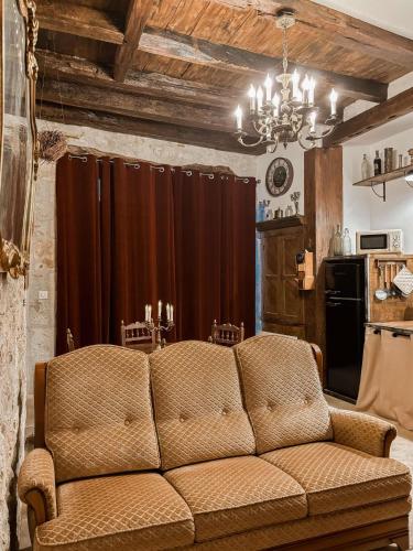 un salon avec un canapé marron et une cuisine dans l'établissement Les sorciers de Lauzerte immersion magique, à Lauzerte