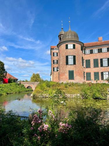 a large brick building next to a river with a bridge at Ferienwohnung Ostseefeuer in Eutin